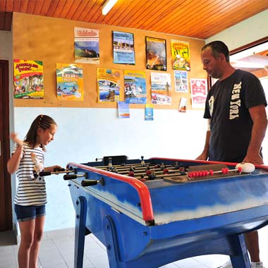 Un père et sa fille jouant au baby-foot dans la salle de jeux du camping près de Vieux-Boucau