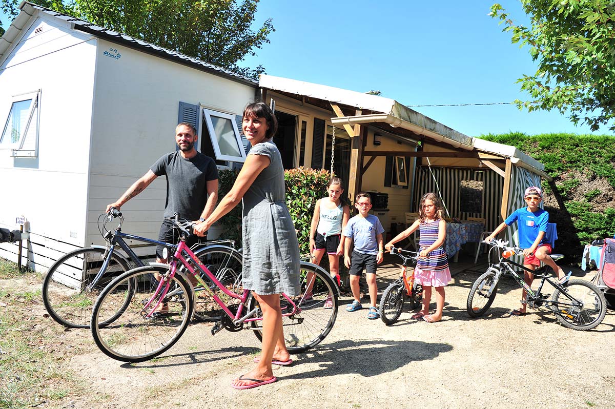 Familia en bicicleta frente a las casas móviles del camping Moussaillon en Messanges