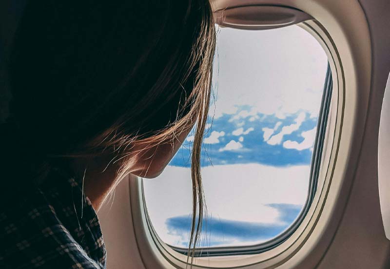 Jeune femme devant le hublot d'un avion en Aquitaine