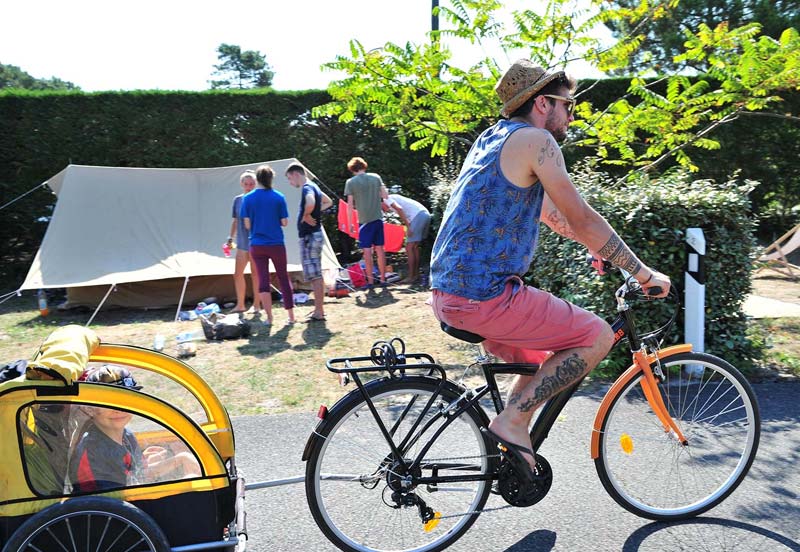 Un vélo devant un emplacement pour tente dans le parc du camping à Messanges