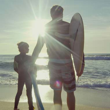 A father and son with a surfboard on a beach in Les Landes near Messanges