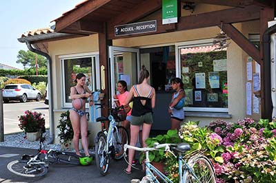 Chicas jóvenes y bicicletas frente a la recepción del camping en Messanges