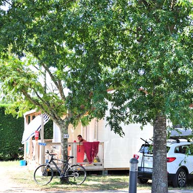 Alquiler de mobil-homes bajo los árboles con bicicleta y coche en el camping de Messanges
