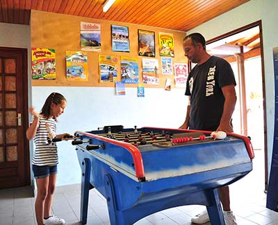 Un père et sa fille jouant au baby-foot dans la salle de jeux du camping près de Vieux-Boucau