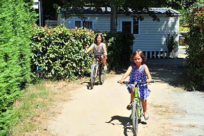 Enfants à vélo devant un mobile en location au camping dans les Landes à Messanges