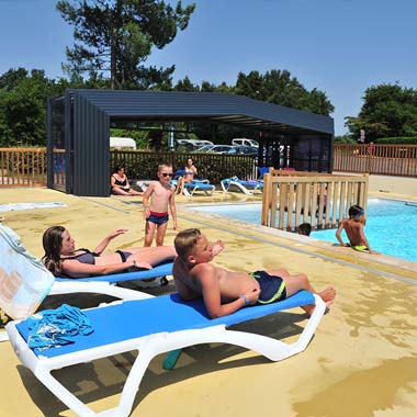 Campers on deckchairs on the swimming pool beach of the Moussaillon campsite in the Landes
