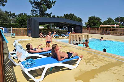 Campers on deckchairs on the swimming pool beach of the Moussaillon campsite in the Landes