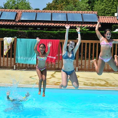 Chicas jóvenes saltando a la piscina en el camping cerca de Capbreton en Messanges