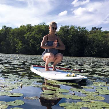 Femme sur un surf en posture de yoga dans les Landes à Messanges