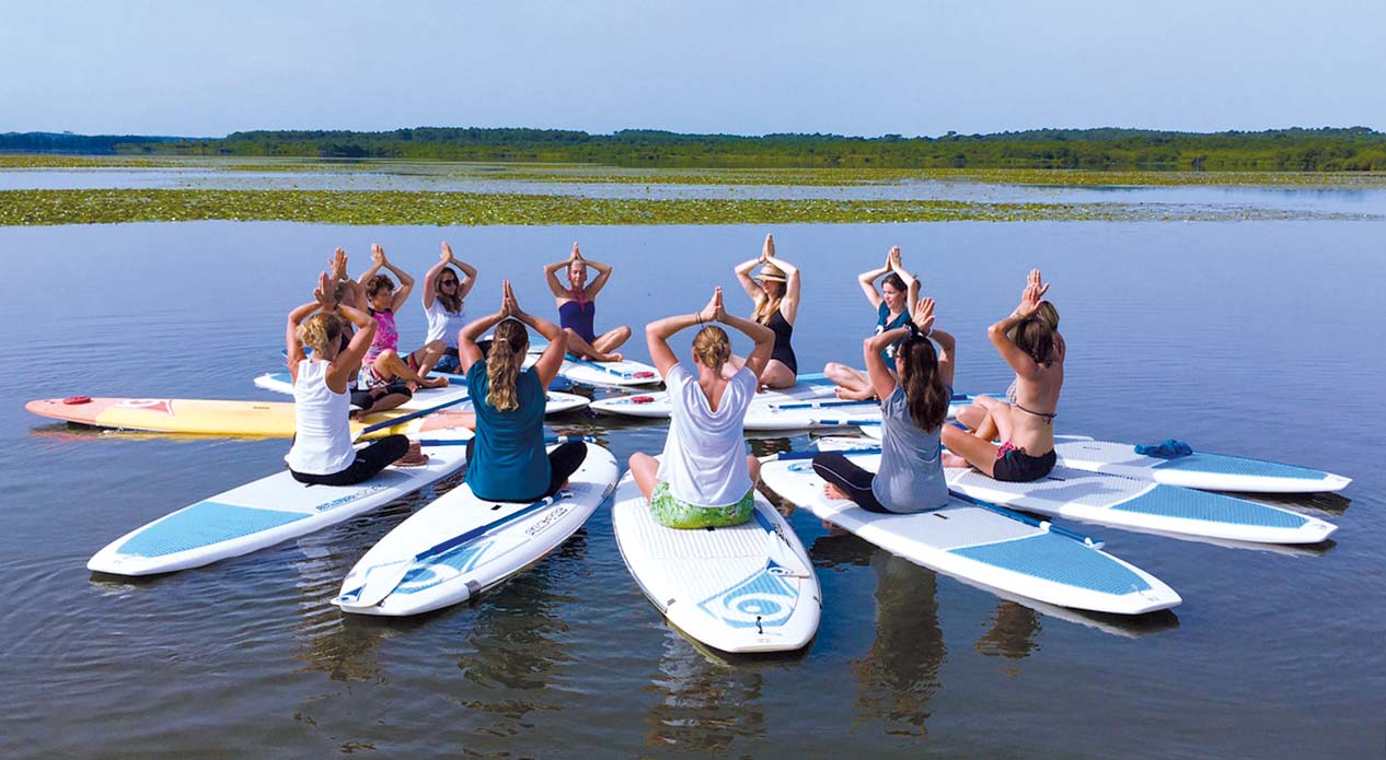 Des surfeurs pratiquant le yoga dans les Landes
